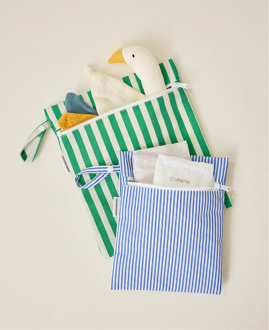 Wet/Dry Bag Set in Stripe print holding a duck lovey in the large green stripe bag and a diaper with wipes in the small blue stripe bag on beige background