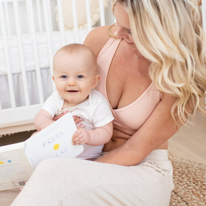 Model sitting on the floor with her baby wearing the French Terry Racerback Nursing & Sleep Bra in Soft Pink