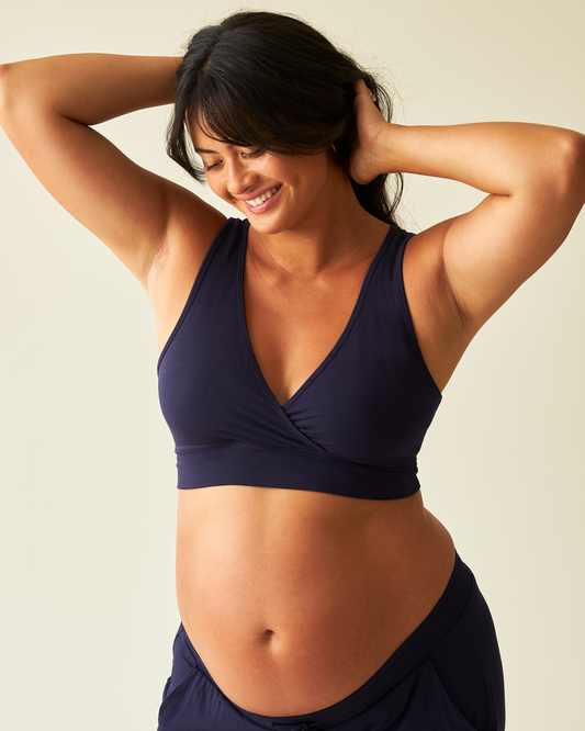 Woman wearing French Terry Racerback Nursing & Sleep Bra in Navy against a beige background @model_info:Zoe is wearing a Medium.