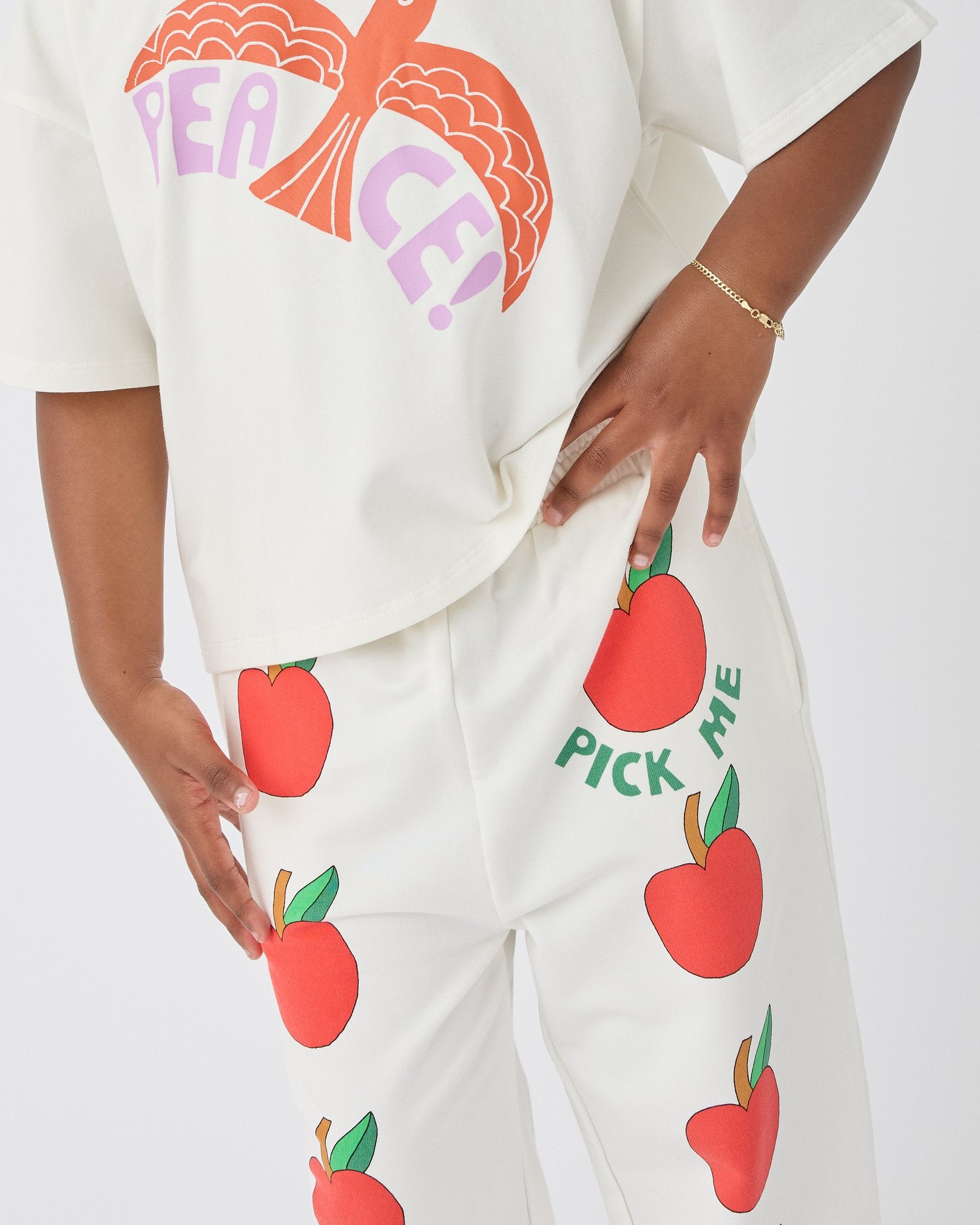 Model is wearing Graphic Tee in White Bird and French Terry Jogger in Ivory Apple on a white background.
