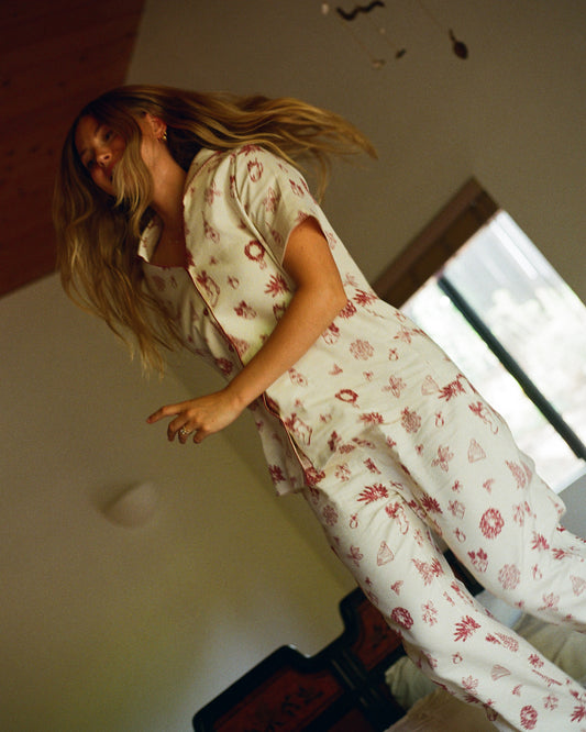 Model is jumping on the bed in a dimly lit room wearing Cotton Bamboo Pajama Set in Cozy Day.