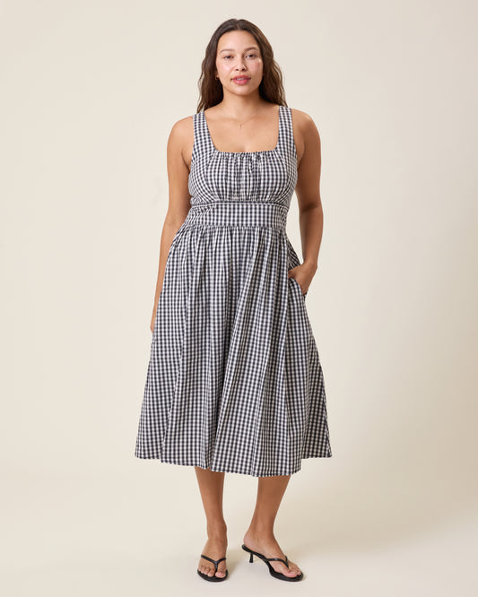 Front view of model wearing Gracie Poplin Nursing Midi Dress in Black & White Gingham on a neutral background and with a hand placed in the dress's pocket@model_info:Alana is 5'7" and wearing a Large.