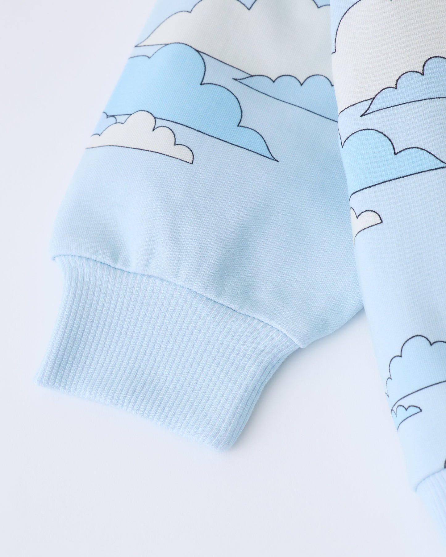 A close-up of sleeve of the Graphic Sweatshirt in Blue Clouds on a white background.