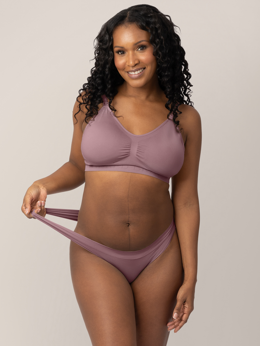 Model wearing the Grow with Me™ Maternity & Postpartum Thong in Twilight holding onto the stretchy waistband on the thong. @model_info:Rashé is wearing a Medium.