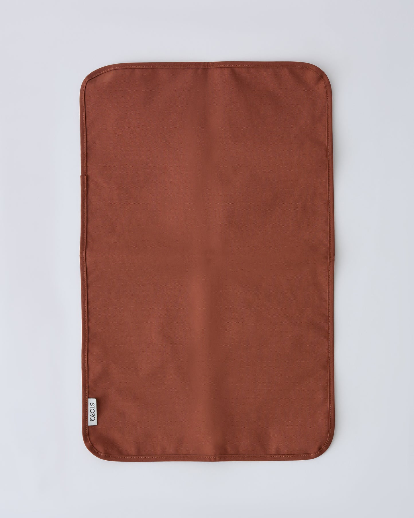 Flat lay of the changing mat that pairs with the Half Moon Crossbody Bag in Cinnamon on a beige background.
