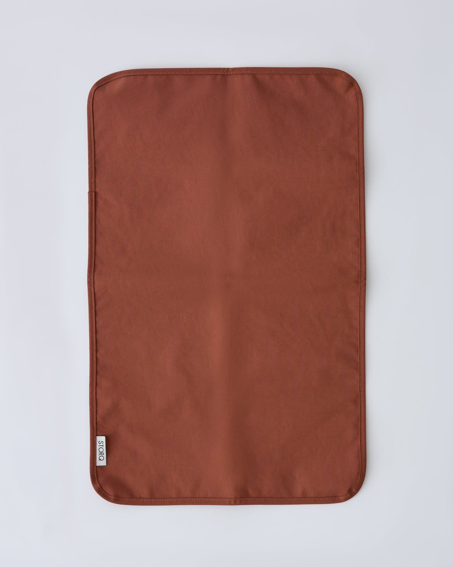 Flat lay of the changing mat that pairs with the Half Moon Crossbody Bag in Cinnamon on a beige background.