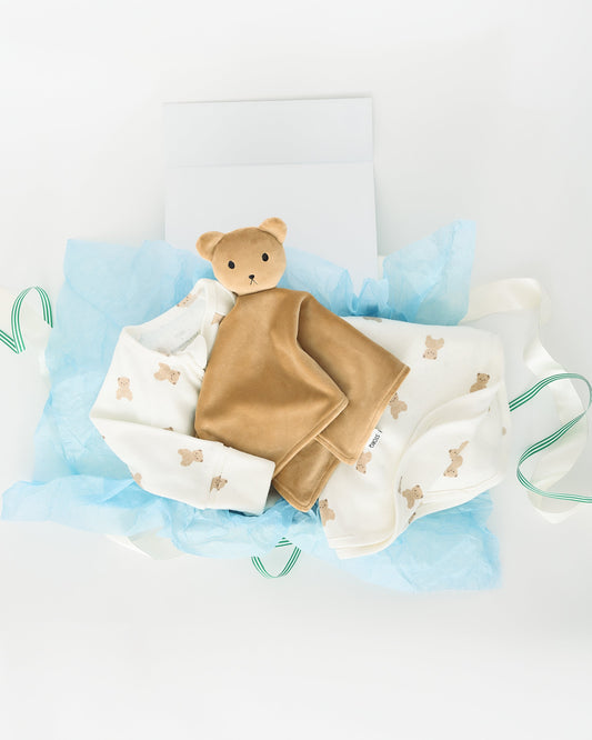The Ivory Bears Hello Baby Gift Set includes: Brown Bear Cuddle Buddy Lovey, Pointelle Baby Pajama in Ivory Bears and Pointelle Swaddle Blanket in Ivory Bears, on a beige background.