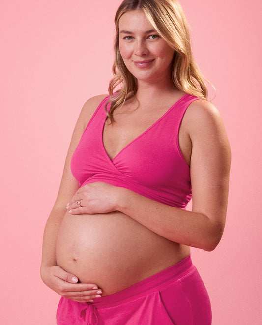 Pregnant woman wearing a pink outfit against a pink background