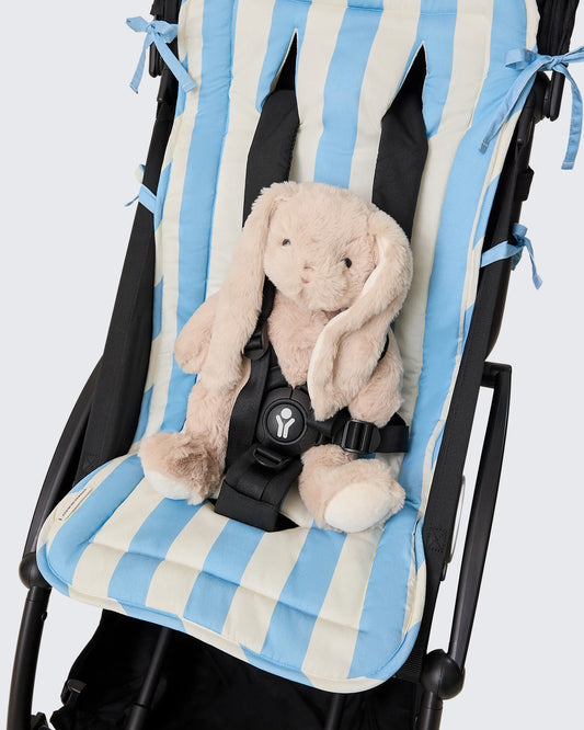 Stroller Party Seat Liner in Blue Wide Stripe pattern on stroller with plush bunny strapped in, on a beige background.