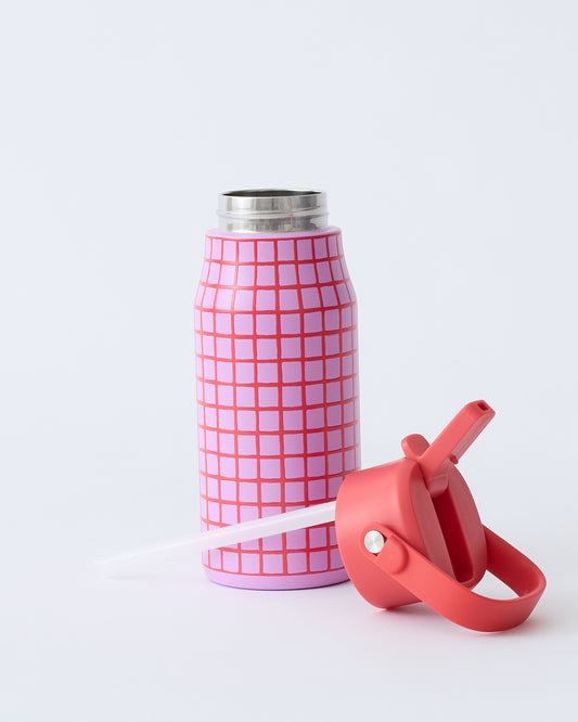 Cool Kid Water Bottle in Orchid Grid with lid and straw laying in front, on a beige background.