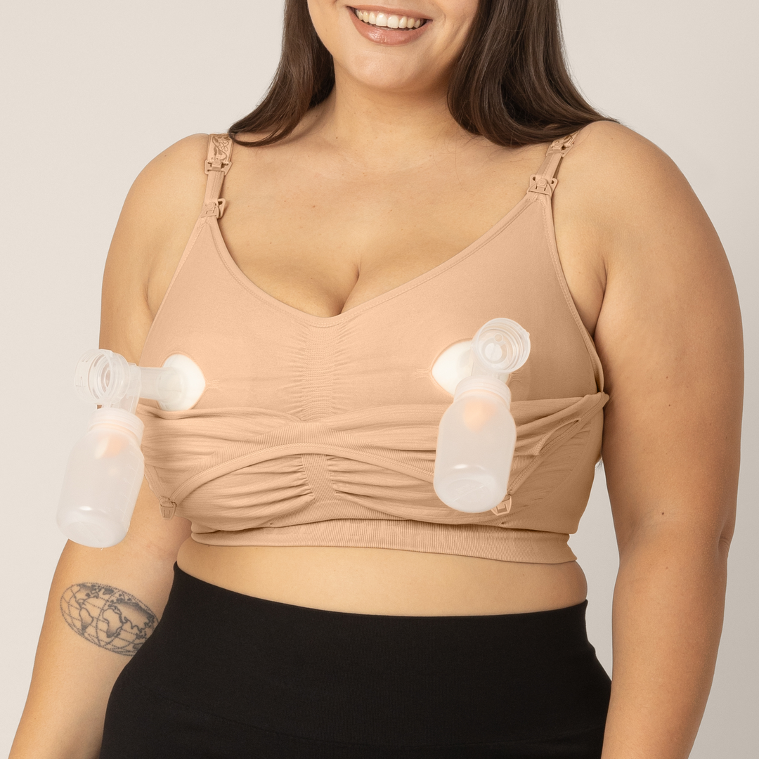 Zoomed in image of model wearing the Sublime Hands-Free Pumping & Nursing Bra in Beige with outer layer unclipped showing pumping access. Pumps are inserted for hands-free pumping capabilities.