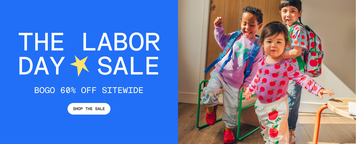 Promotional image with blue background and white text that reads, The Labor Day Sale, BOGO 60% Off sitewide. White button and black text that reads, Shop the Sale. Group image of three models wearing Cool Kid Backpacks, Graphic Tee in Blue Apple, Long Sleeve Bamboo Onesie Two-Pack in Apple, Graphic Sweatshirt in Purple Bird, French Terry Jogger in Blue Clouds and French Terry Jogger in Ivory Apple in a sunlit room.