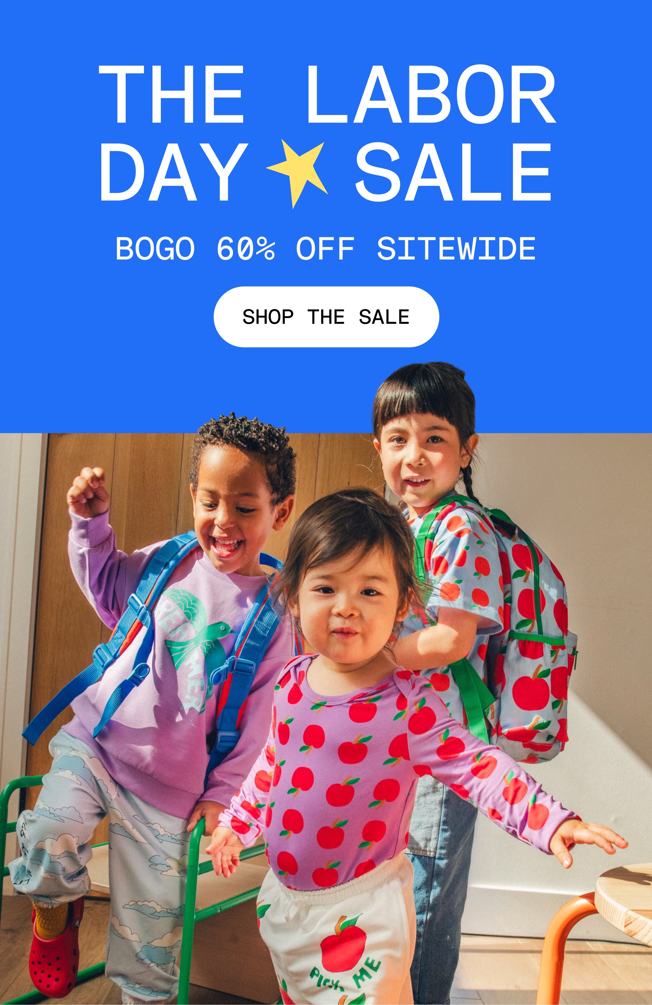 Promotional image with blue background and white text that reads, The Labor Day Sale, BOGO 60% Off sitewide. White button and black text that reads, Shop the Sale. Group image of three models wearing Cool Kid Backpacks, Graphic Tee in Blue Apple, Long Sleeve Bamboo Onesie Two-Pack in Apple, Graphic Sweatshirt in Purple Bird, French Terry Jogger in Blue Clouds and French Terry Jogger in Ivory Apple in a sunlit room.