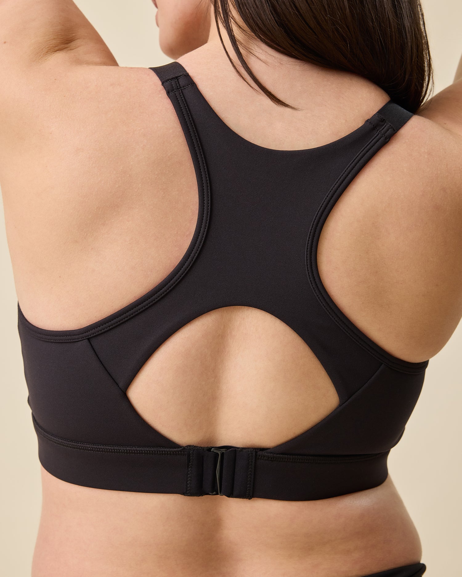 Back view on the High Impact Nursing Sports Bra in Black on a beige background