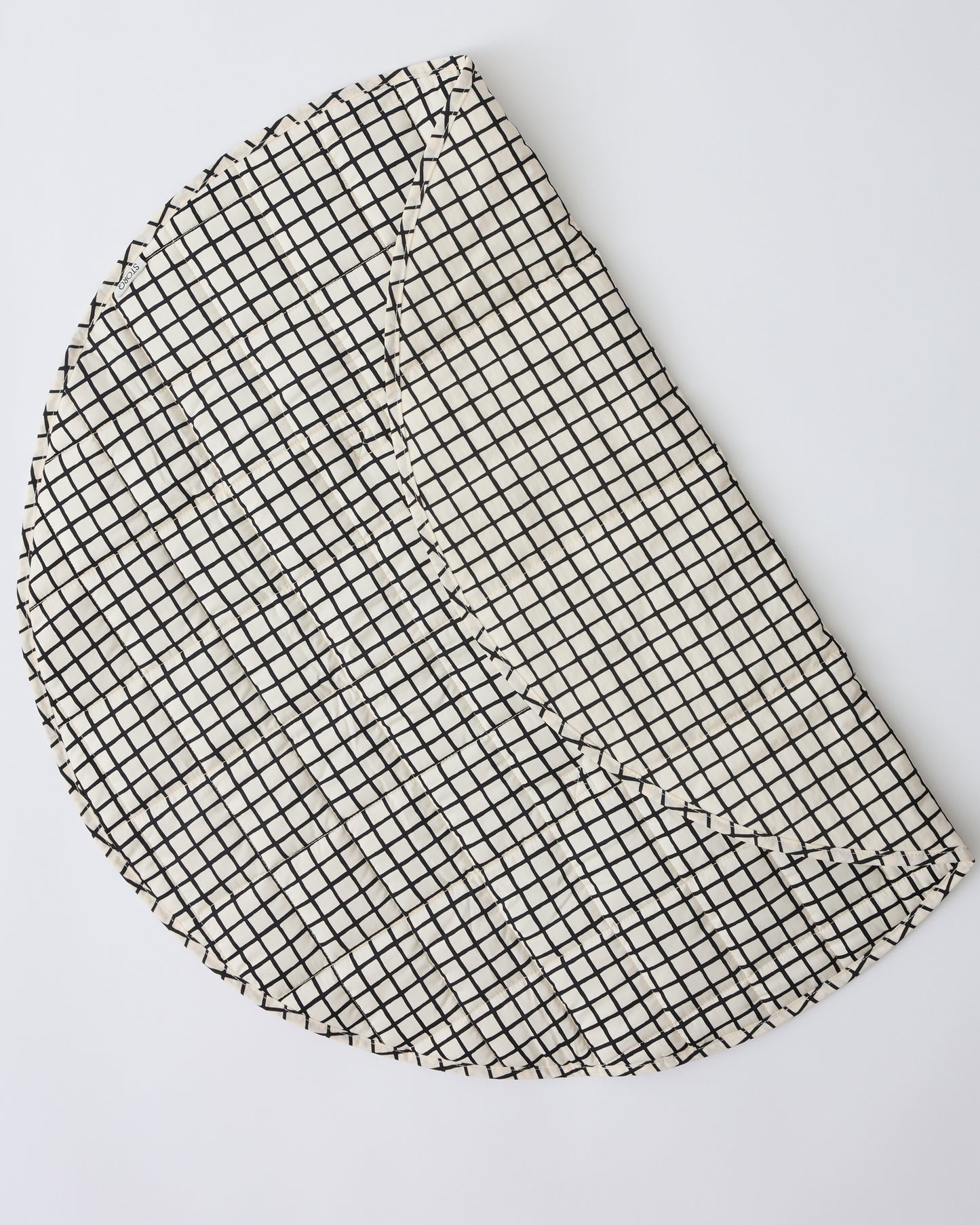 Inside/Outside Play Mat in Black Grid folded over to show the water-resistant exterior, on a beige background.