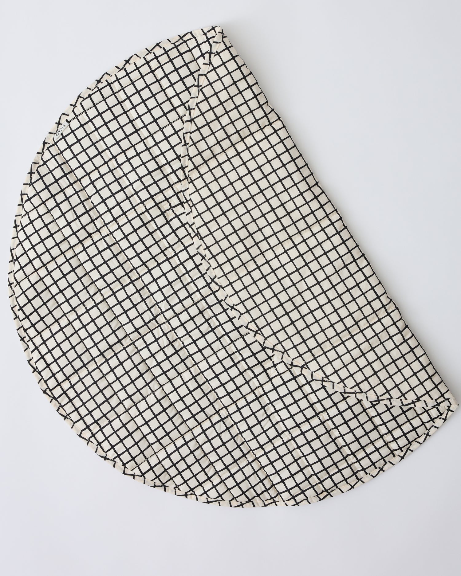 Inside/Outside Play Mat in Black Grid folded over to show the water-resistant exterior, on a beige background.