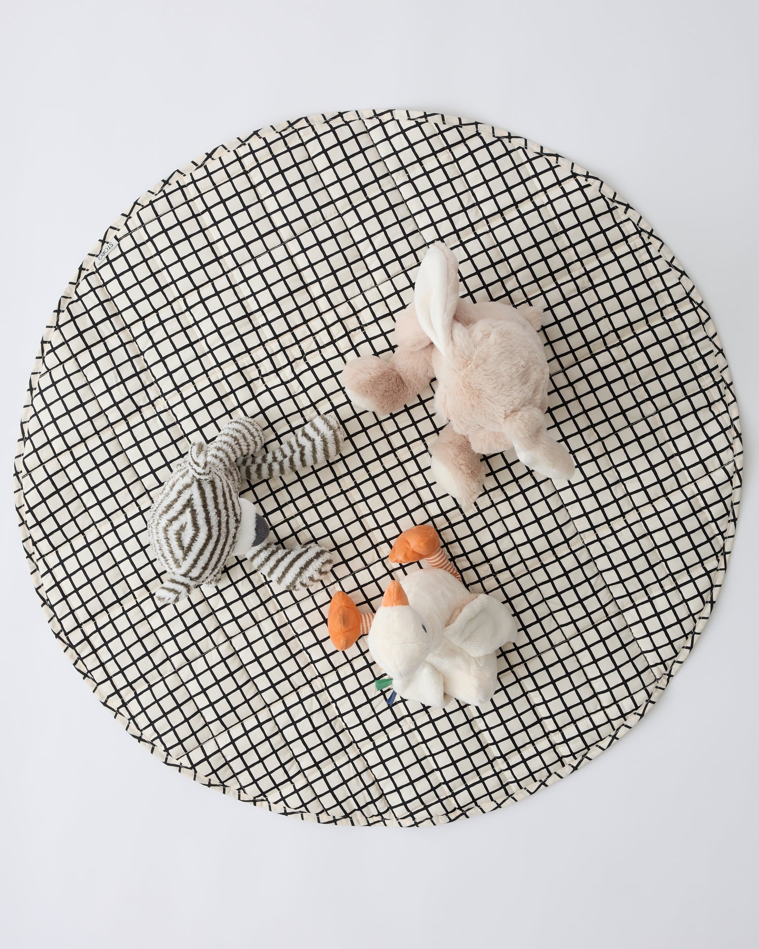 Inside/Outside Play Mat in Black Grid with three animal lovey dolls sitting ontop, on a beige background.