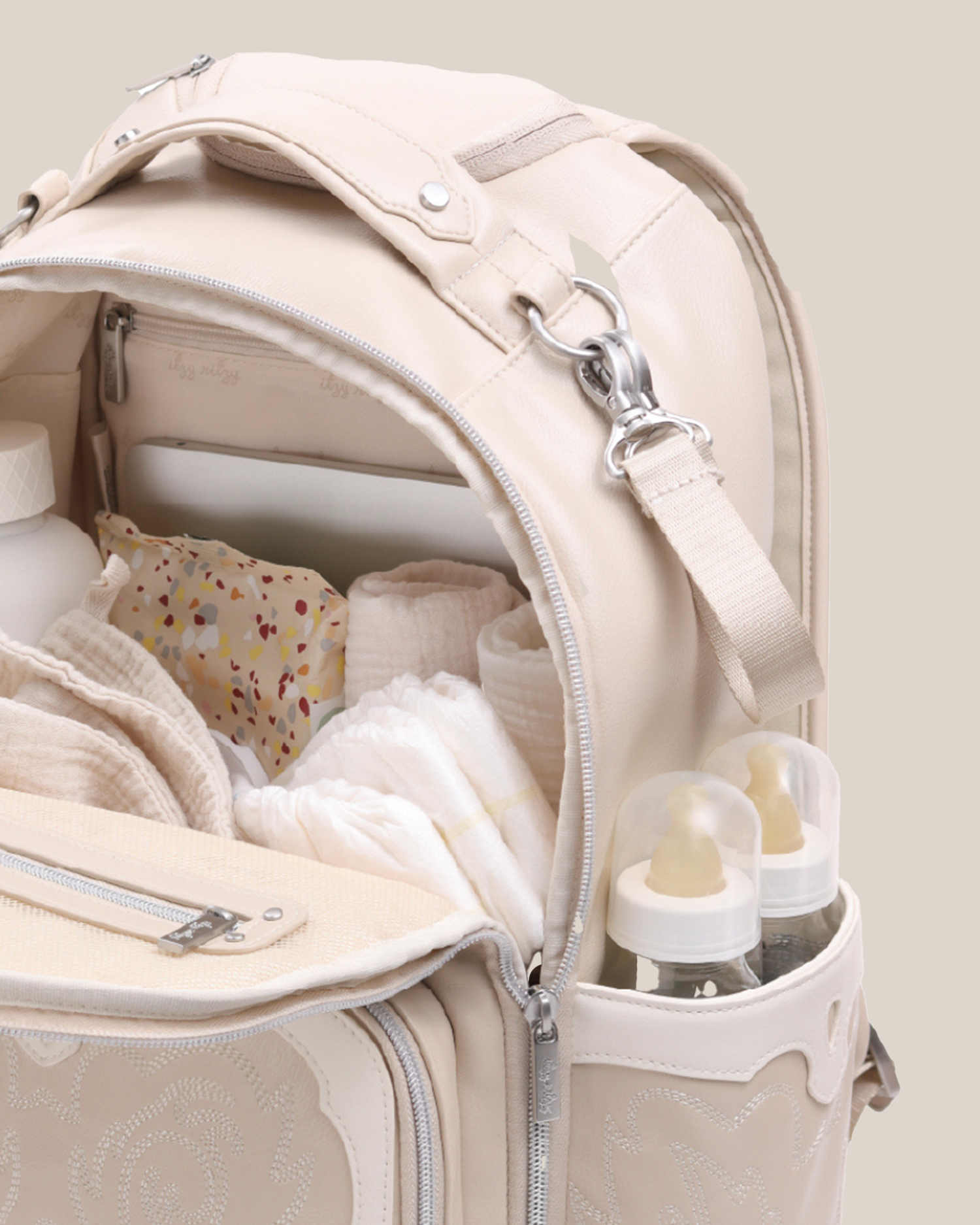 Close up of the Itzy Ritzy - Nash Boss Plus™ Diaper Bag in Oat, opened and showing what can be carried in it