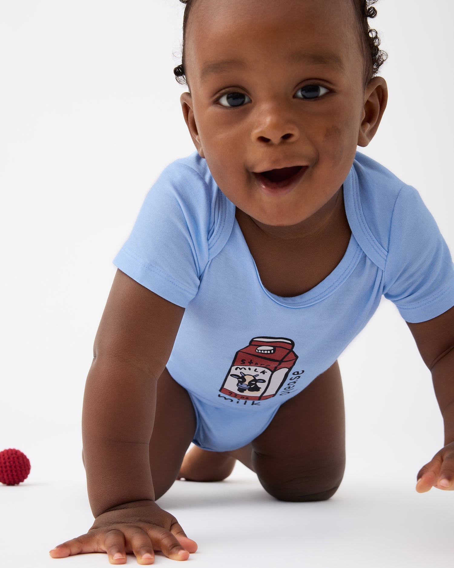 Baby is crawling and wearing Baby Onesie Two-Pack in Milk Please on a beige background
