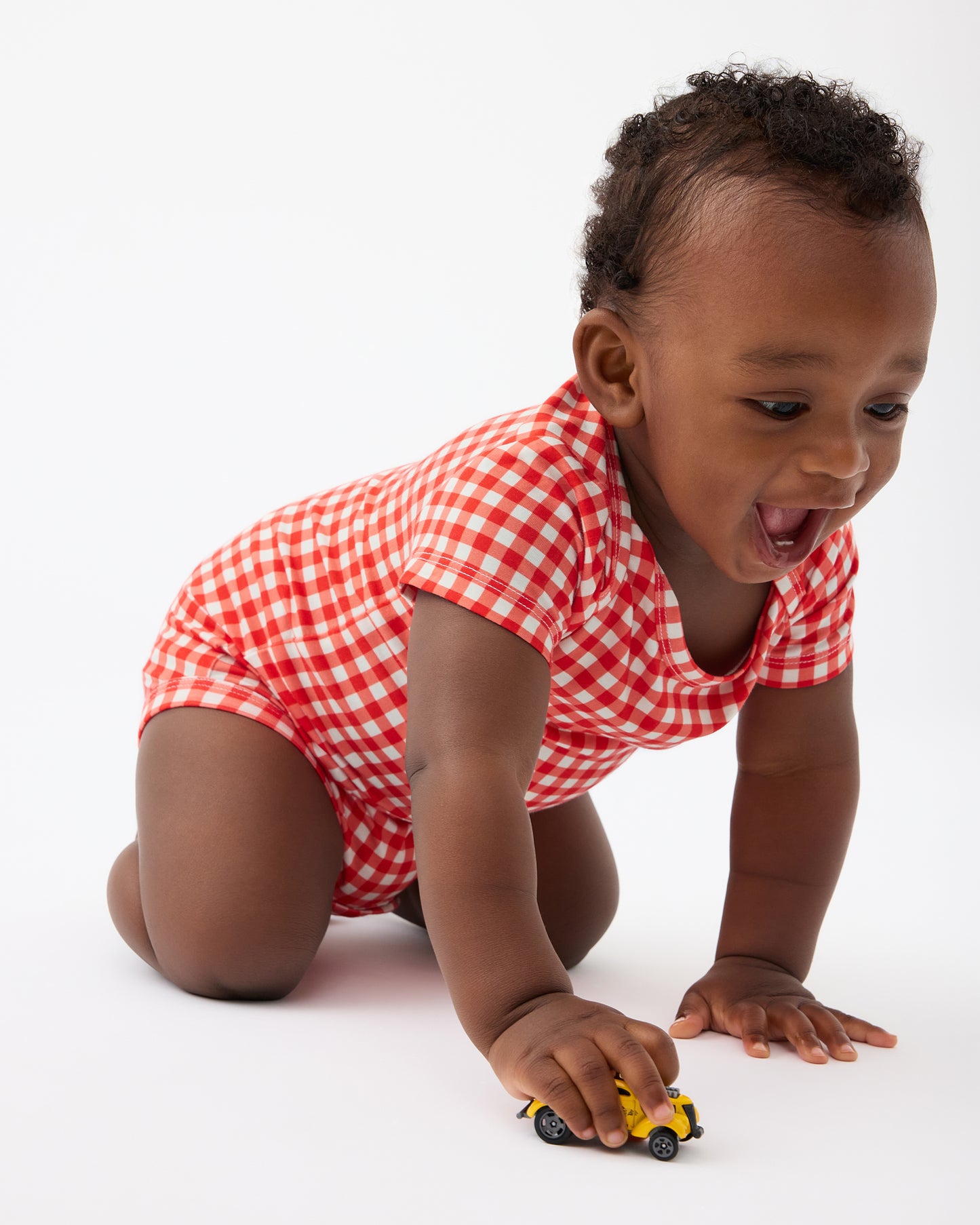 Baby is crawling and wearing Red Gingham of the Baby Onesie Two-Pack in Red & Blue Gingham@model_info:Jobadaiah is wearing 6-12 months.