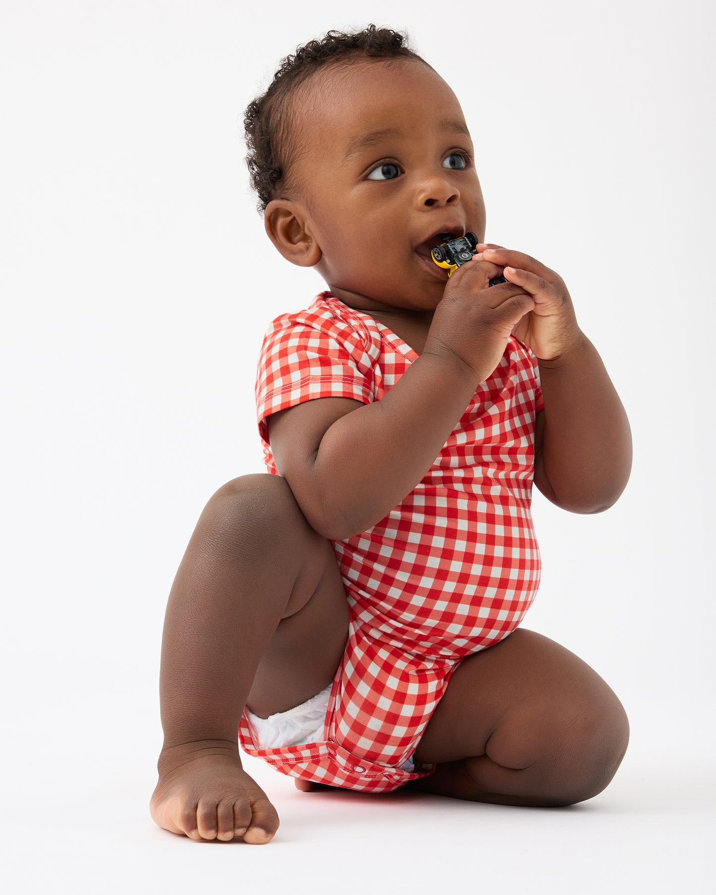 Baby is playing with toy car and wearing Red Gingham of the Baby Onesie Two-Pack in Red & Blue Gingham