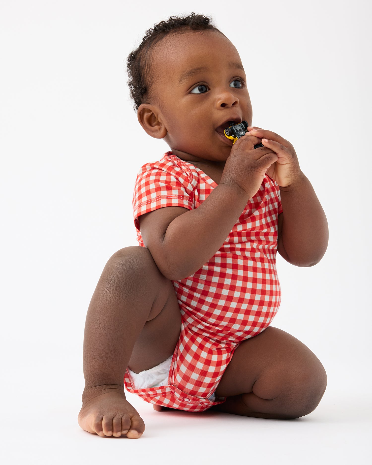 Baby is playing with toy car and wearing Red Gingham of the Baby Onesie Two-Pack in Red & Blue Gingham