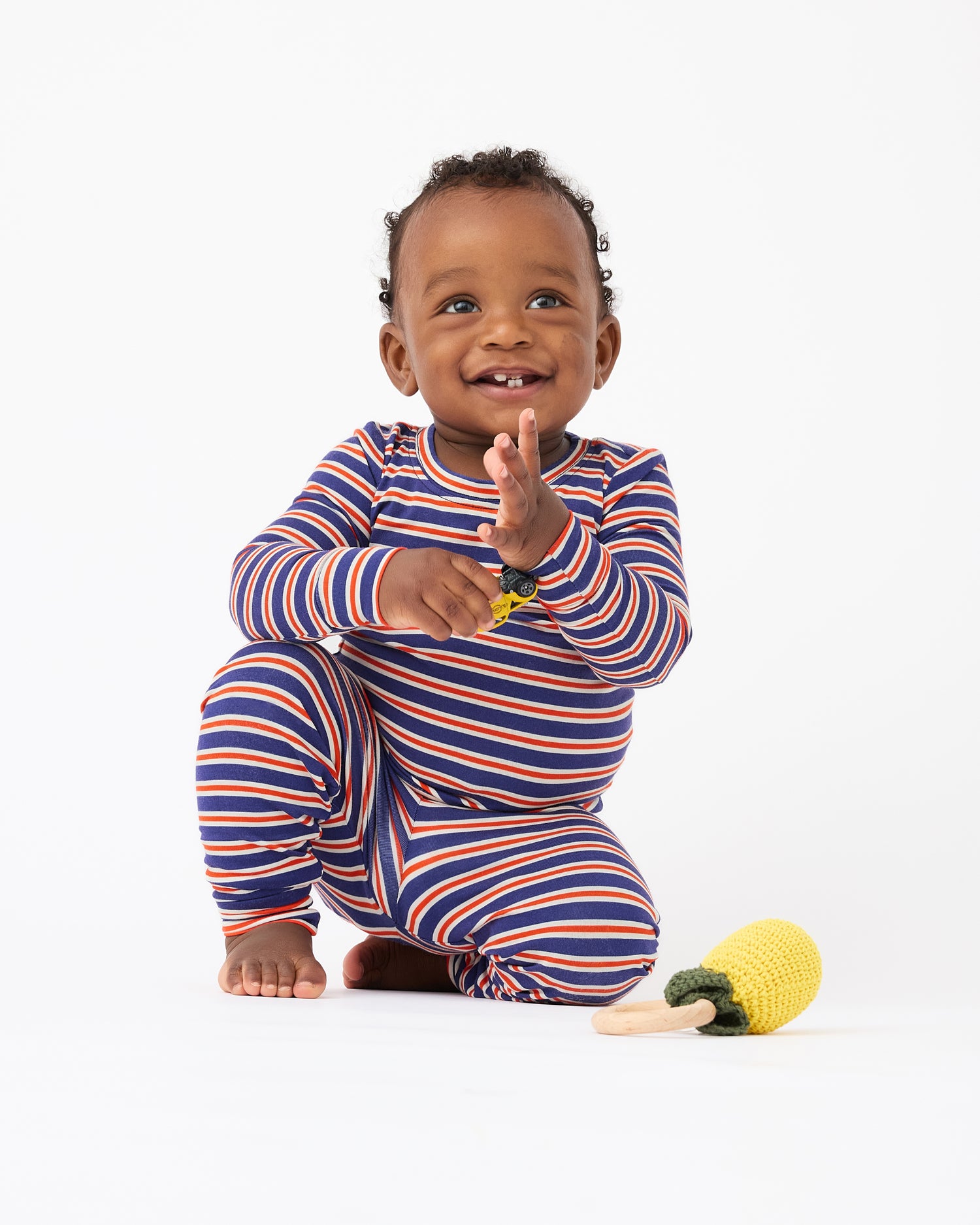 Baby is playing with toy car and wearing wearing Bamboo Baby Two-Piece Pajama Set in Preppy Stripe on a beige background@model_info:Jobadaiah is wearing 12-18 months.