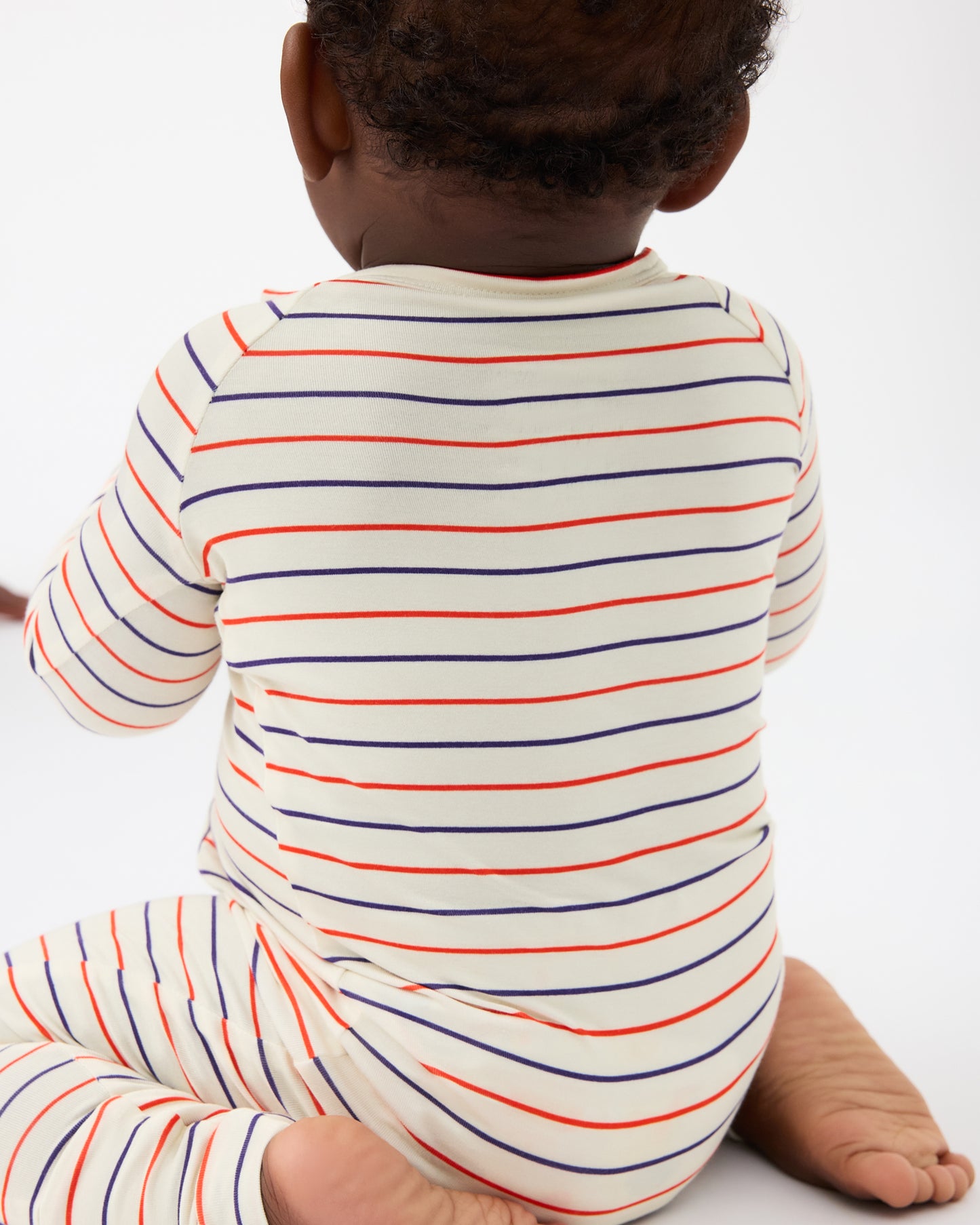 Back view of baby wearing Bamboo Baby Pajama in Pencil Stripe on a beige background