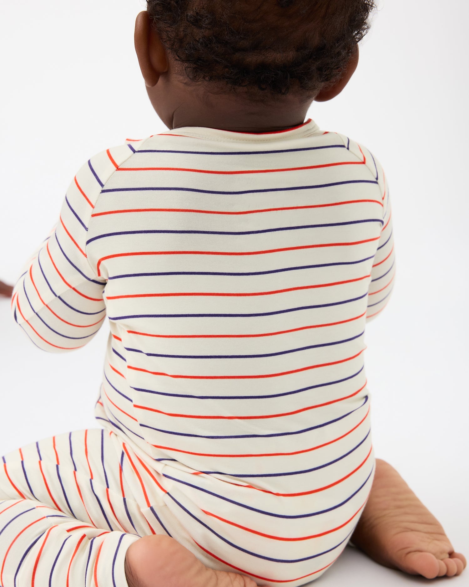 Back view of baby wearing Bamboo Baby Pajama in Pencil Stripe on a beige background