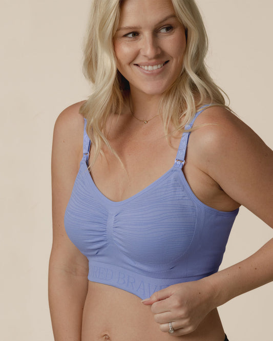 Front view of model wearing the Sublime® Hands-Free Pumping & Nursing Bra in Blue Wisteria, pulling at band showing stretch of fabric@model_info:Maddy is wearing a Small.