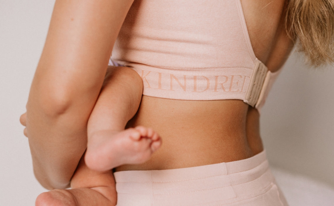 Cropped in image of model holding infant, showing Kindred Bravely bra band