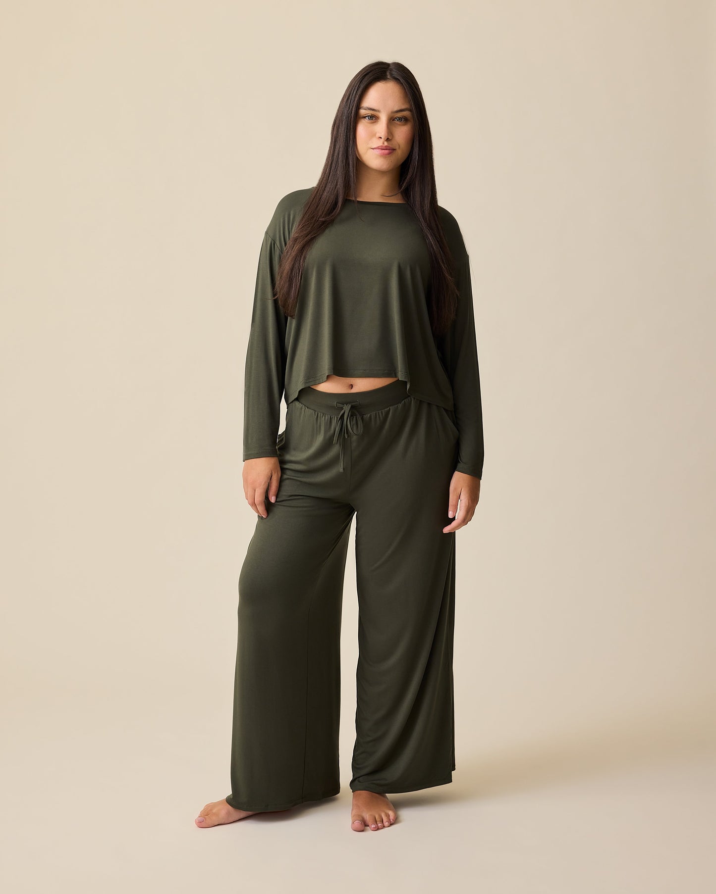 Model is wearing Aria Bamboo Casual Cropped Long Sleeve Top and Aria Bamboo Casual Lounge Pant in Thyme on a beige background.