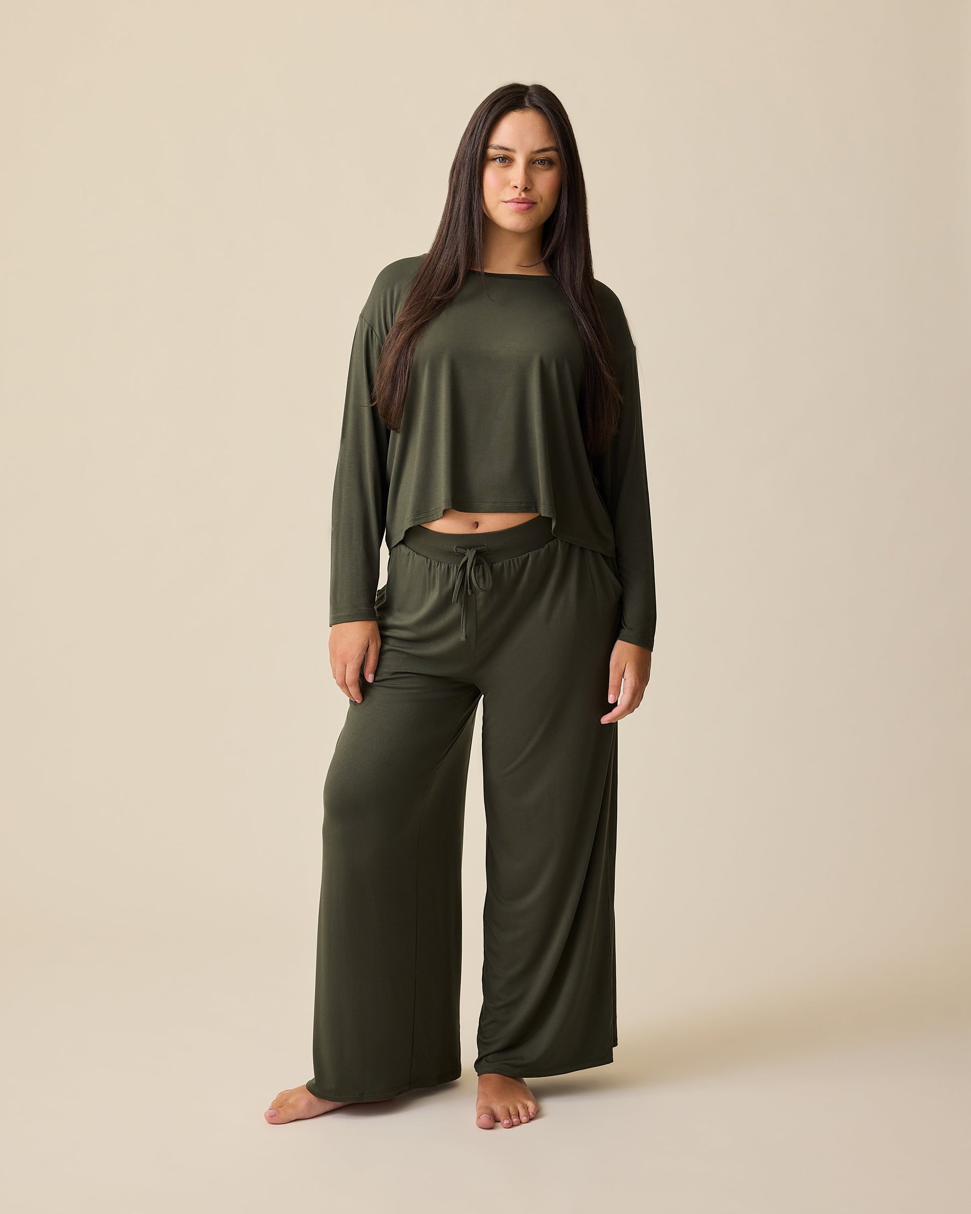 Model is wearing Aria Bamboo Casual Cropped Long Sleeve Top and Aria Bamboo Casual Lounge Pant in Thyme on a beige background.