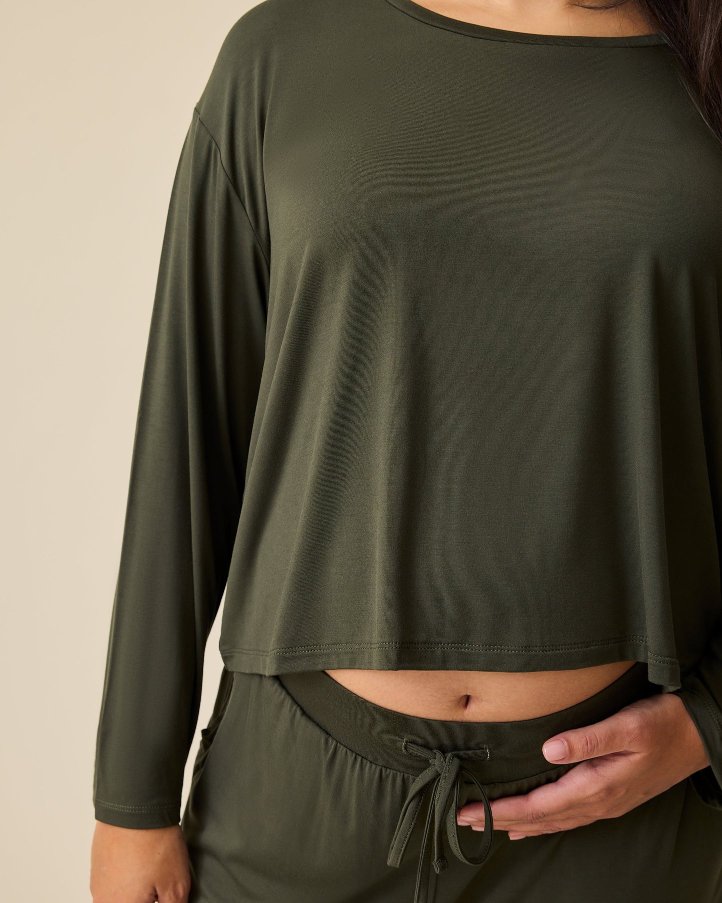 Close up of the sleeve on model wearing Aria Bamboo Casual Cropped Long Sleeve Top in Thyme on a beige background.