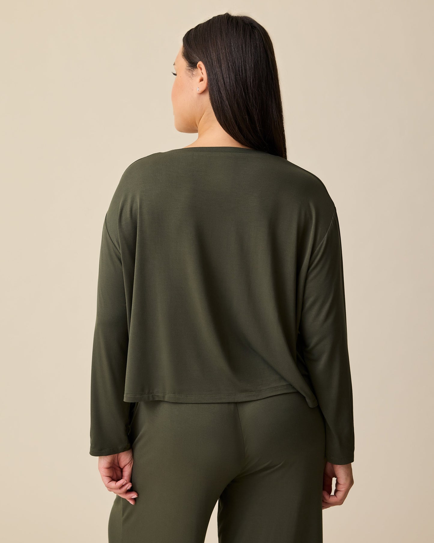 Back view of model wearing Aria Bamboo Casual Cropped Long Sleeve Top and Aria Bamboo Casual Lounge Pant in Thyme on a beige background.