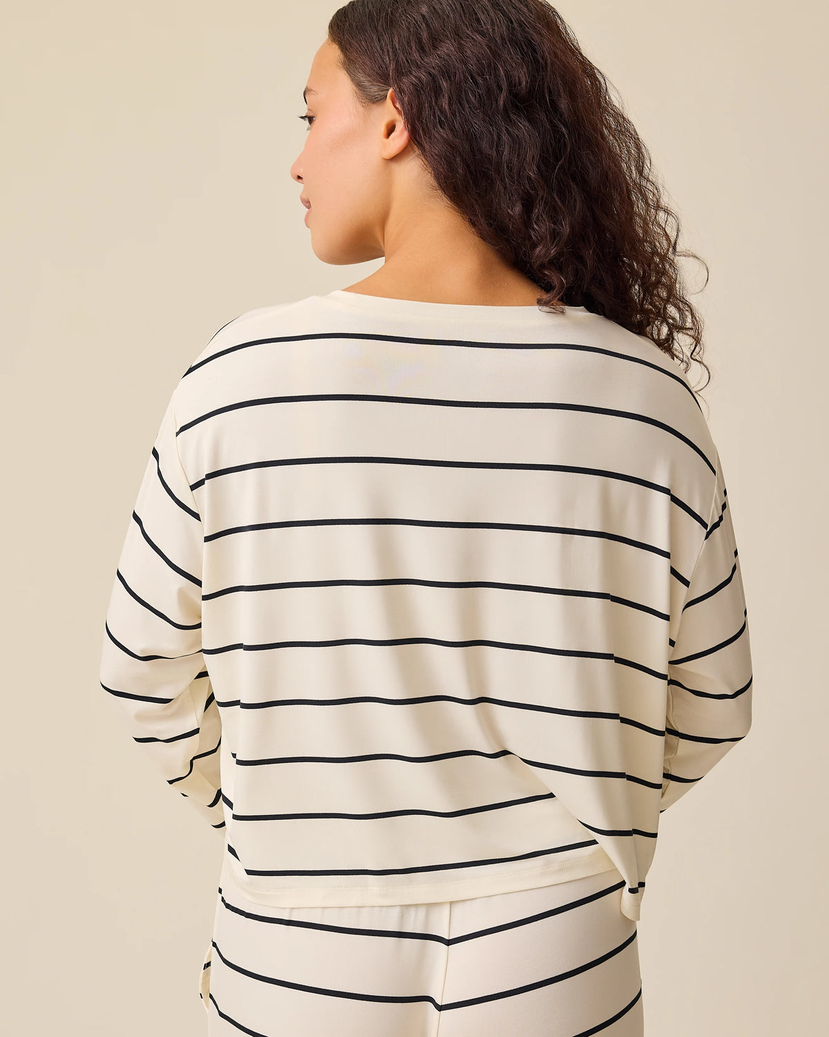 Back view of model wearing Aria Bamboo Casual Cropped Long Sleeve Top in White & Black Stripe and Aria Bamboo Casual Lounge Pant in White & Black Stripe on a beige background.