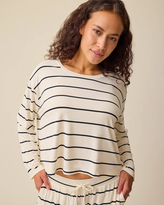 Model is wearing Aria Bamboo Casual Cropped Long Sleeve Top in White & Black Stripe and Aria Bamboo Casual Lounge Pant in White & Black Stripe on a beige background. @model_info:Sadie is wearing a Medium.
