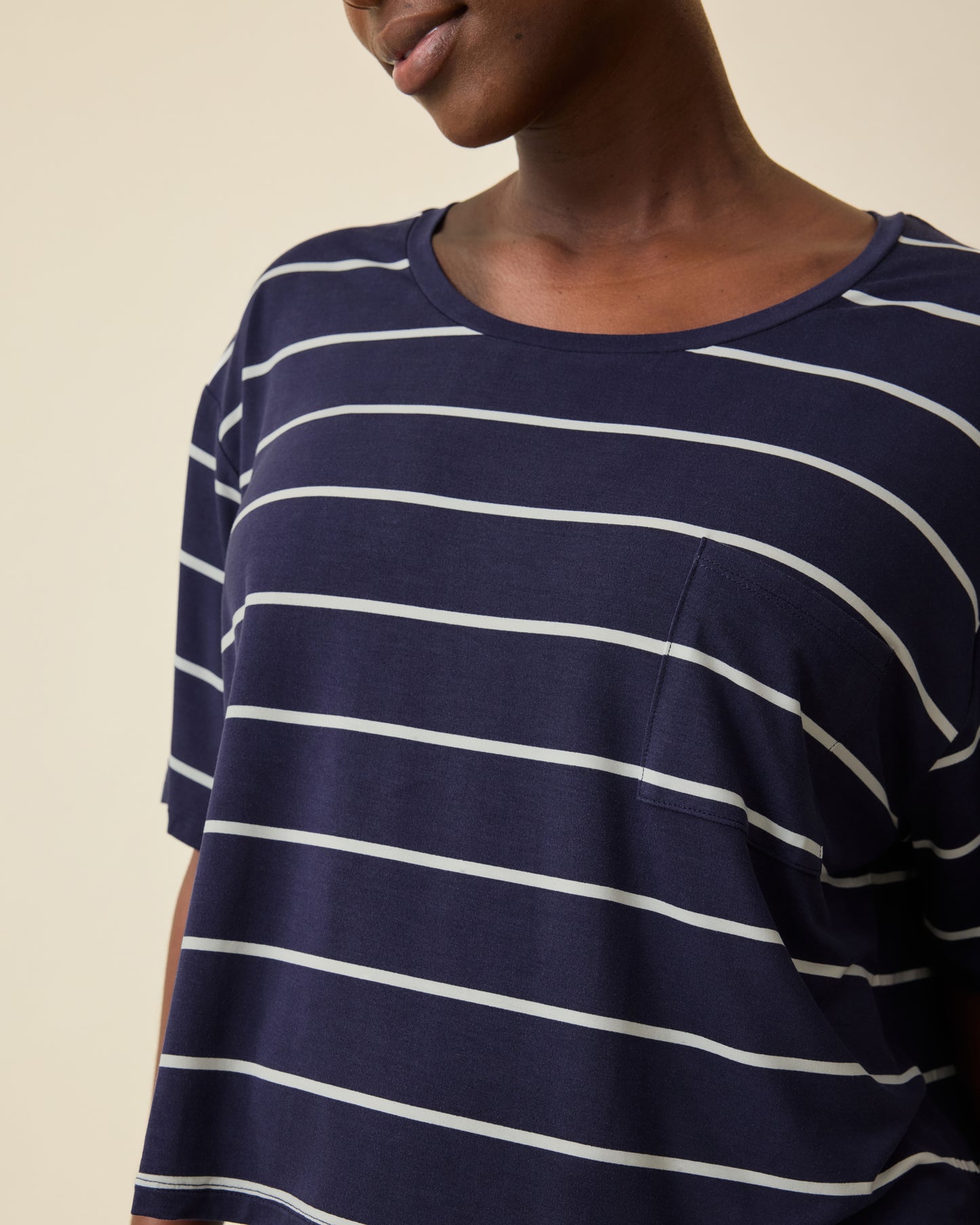 Model is wearing Aria Bamboo Casual Cropped Short Sleeve Top in Navy & White Stripe on a beige background.