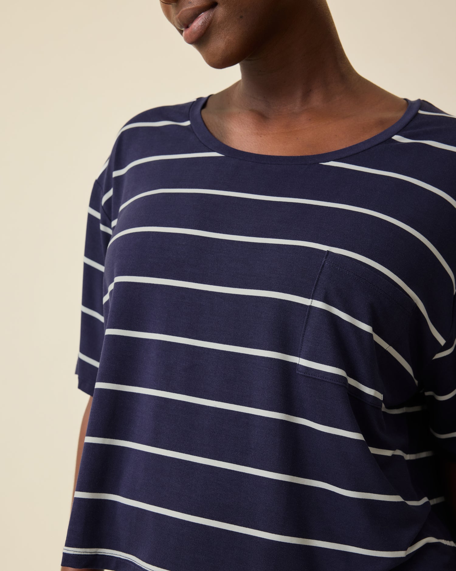 Model is wearing Aria Bamboo Casual Cropped Short Sleeve Top in Navy & White Stripe on a beige background.