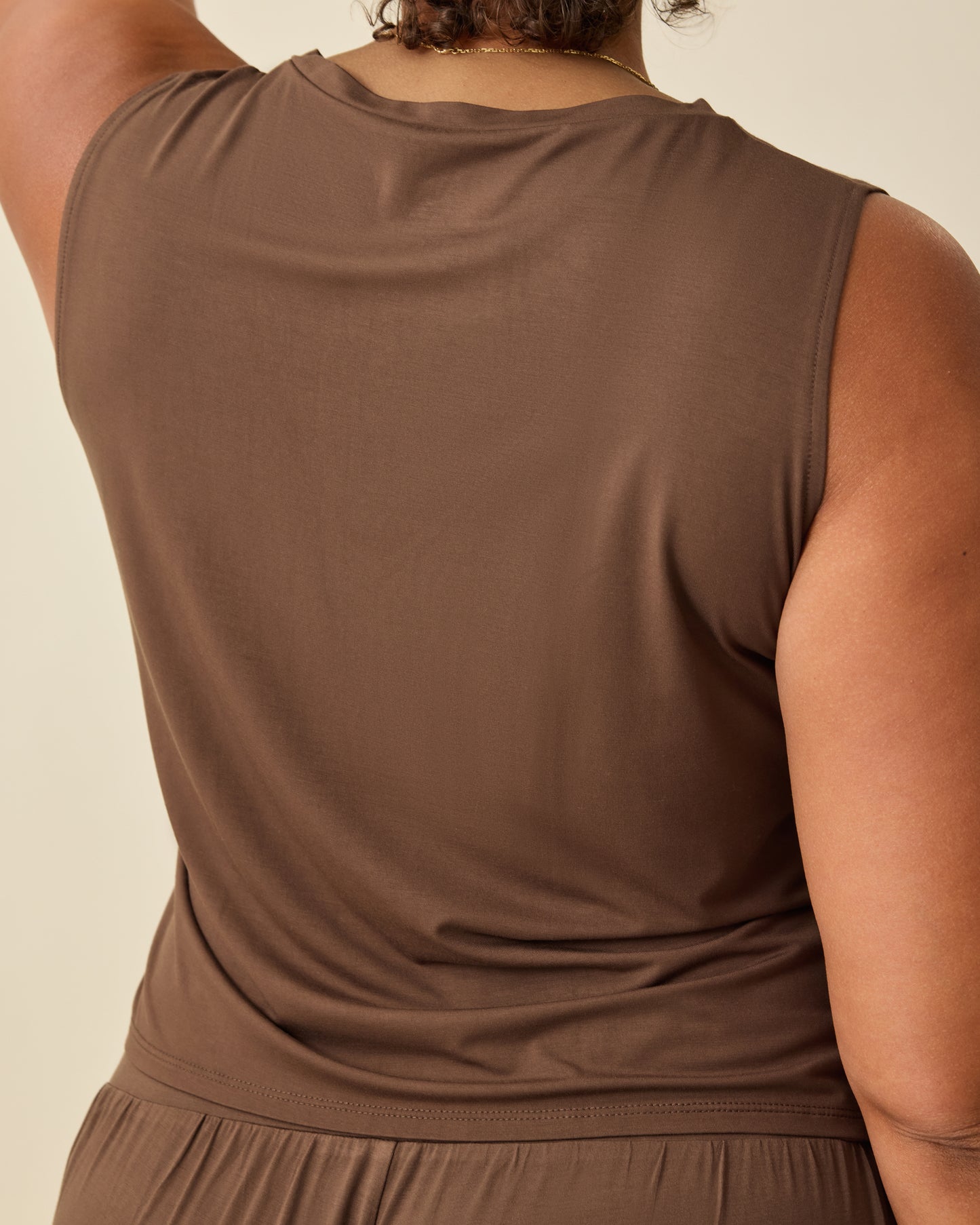 Back view of the Aria Bamboo Cropped V-neck Tank in Chocolate on a beige backgound.