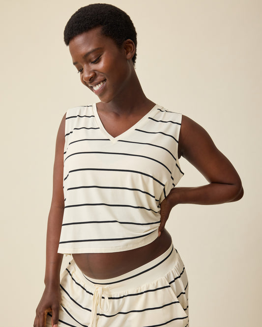 Model is wearing Aria Bamboo Cropped V-neck Tank in White & Black Stripe and Aria Bamboo Casual Lounge Short in White & Black Stripe on a beige background. @model_info:Anna is wearing a Small.