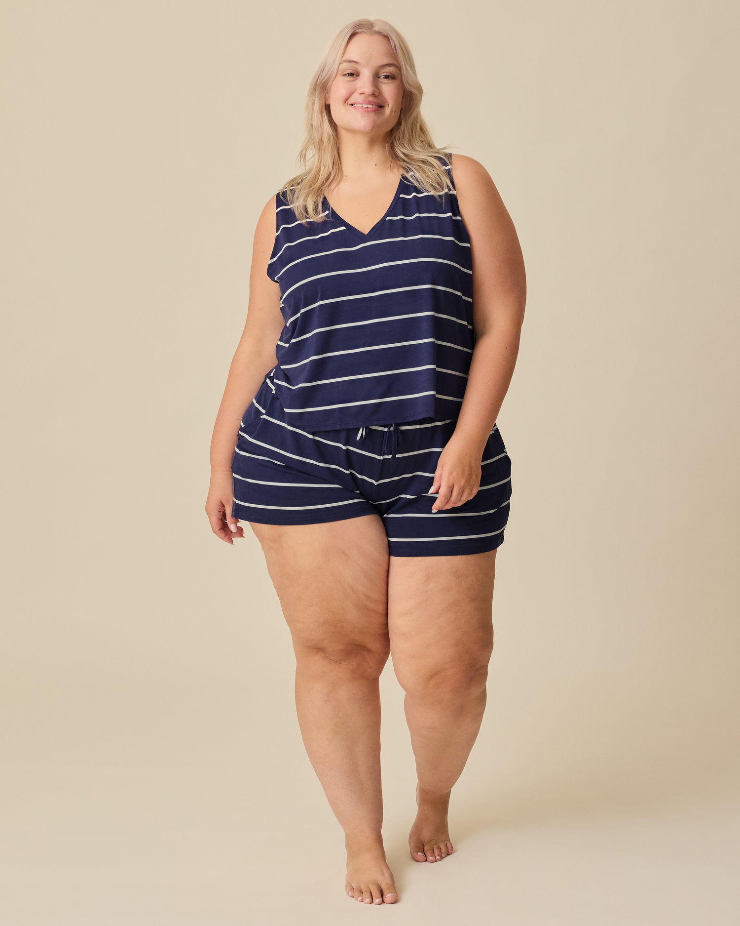 Model is wearing Aria Bamboo Cropped V-neck Tank and Aria Bamboo Casual Lounge Short in Navy & White Stripe on a beige background.