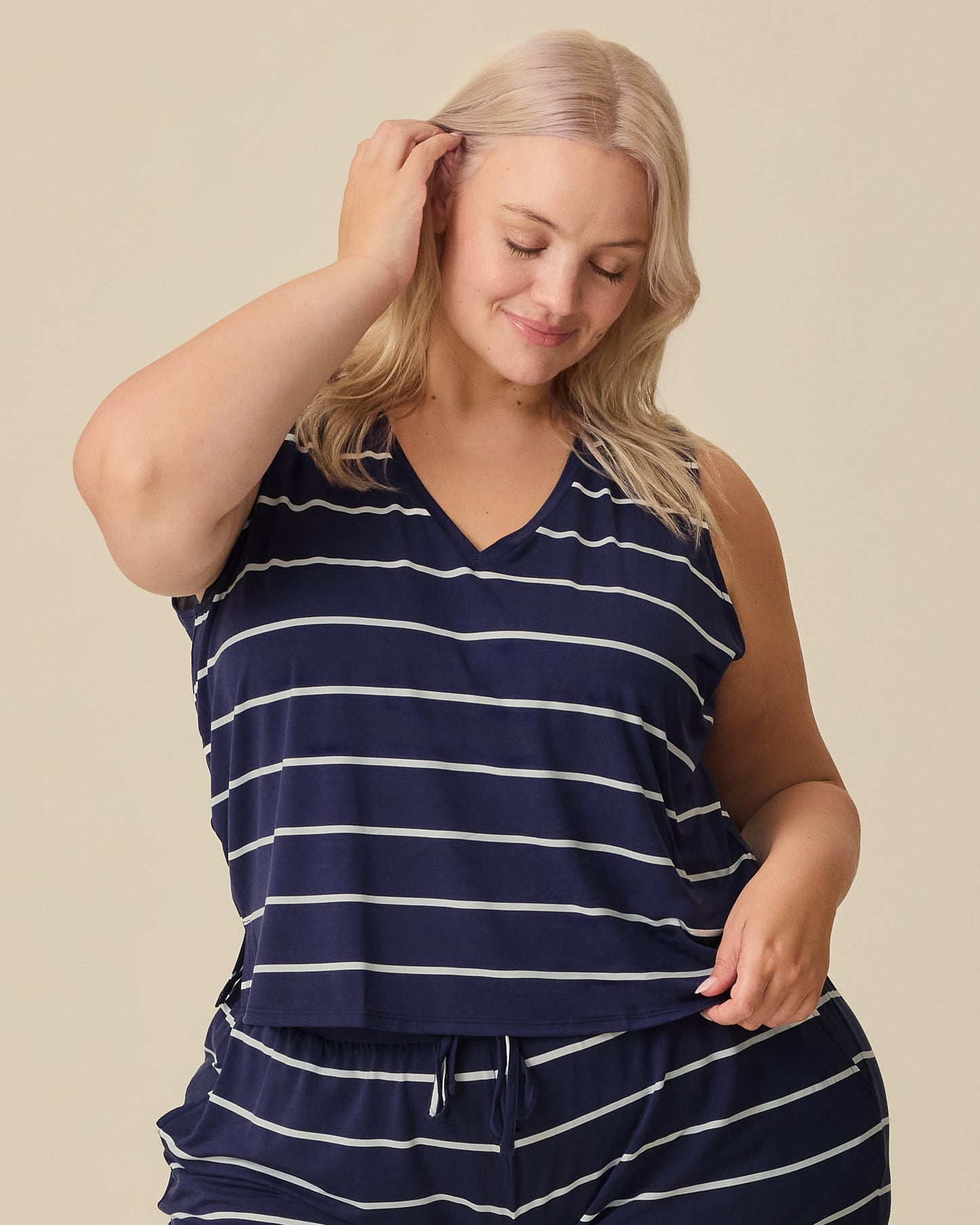 Model is wearing Aria Bamboo Cropped V-neck Tank and Aria Bamboo Casual Lounge Short in Navy & White Stripe on a beige background.@model_info:Allie is wearing a 1X.