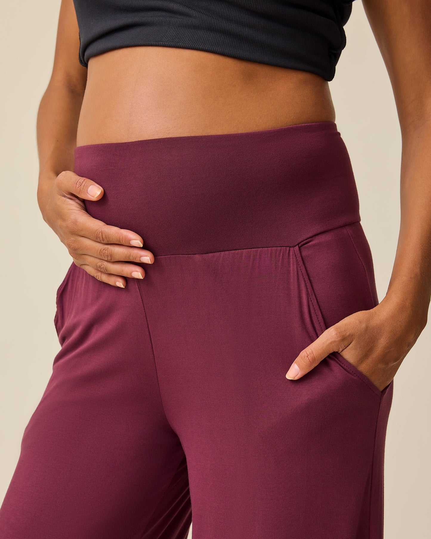 Close up of waist on model wearing  Bamboo Wide Leg Maternity & Postpartum Lounge Pant in Fig and Ribbed Bamboo Racerback Nursing Tank in Black on a beige background. 