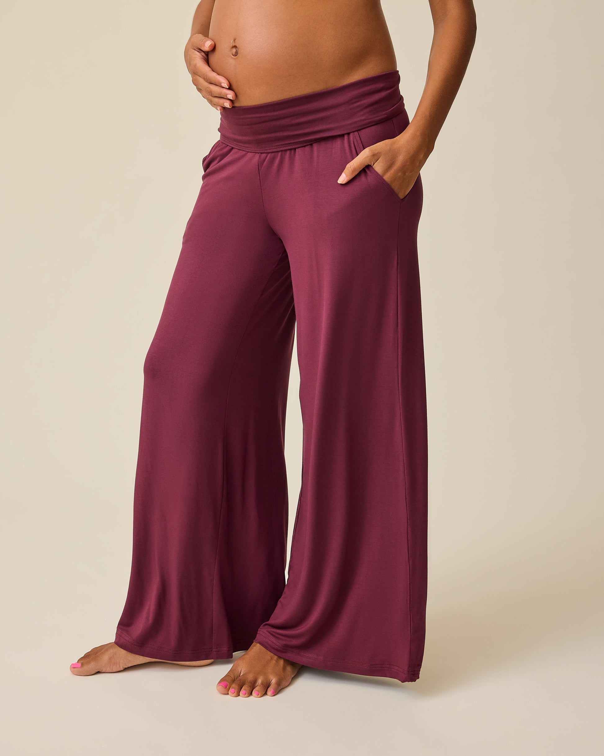 Model is wearing Bamboo Wide Leg Maternity & Postpartum Lounge Pant in Fig on a beige background. 