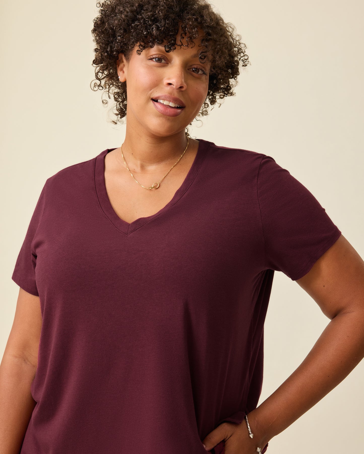 Close up of the Modal V-neck Nursing T-shirt in Deep Burgundy on a beige background. 