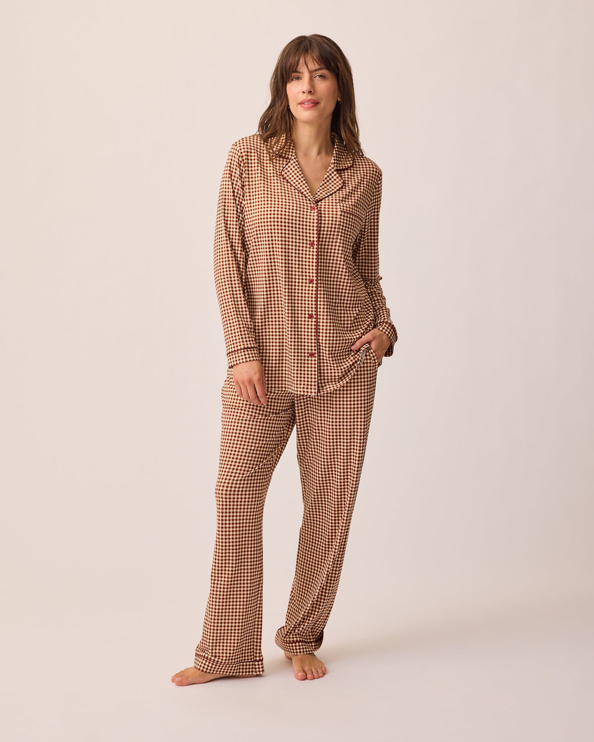 Model is wearing Clea Bamboo Long Sleeve Pajama Set in Auburn Gingham, on a beige background.@model_info:KJ is 5'9" and wearing a Medium.