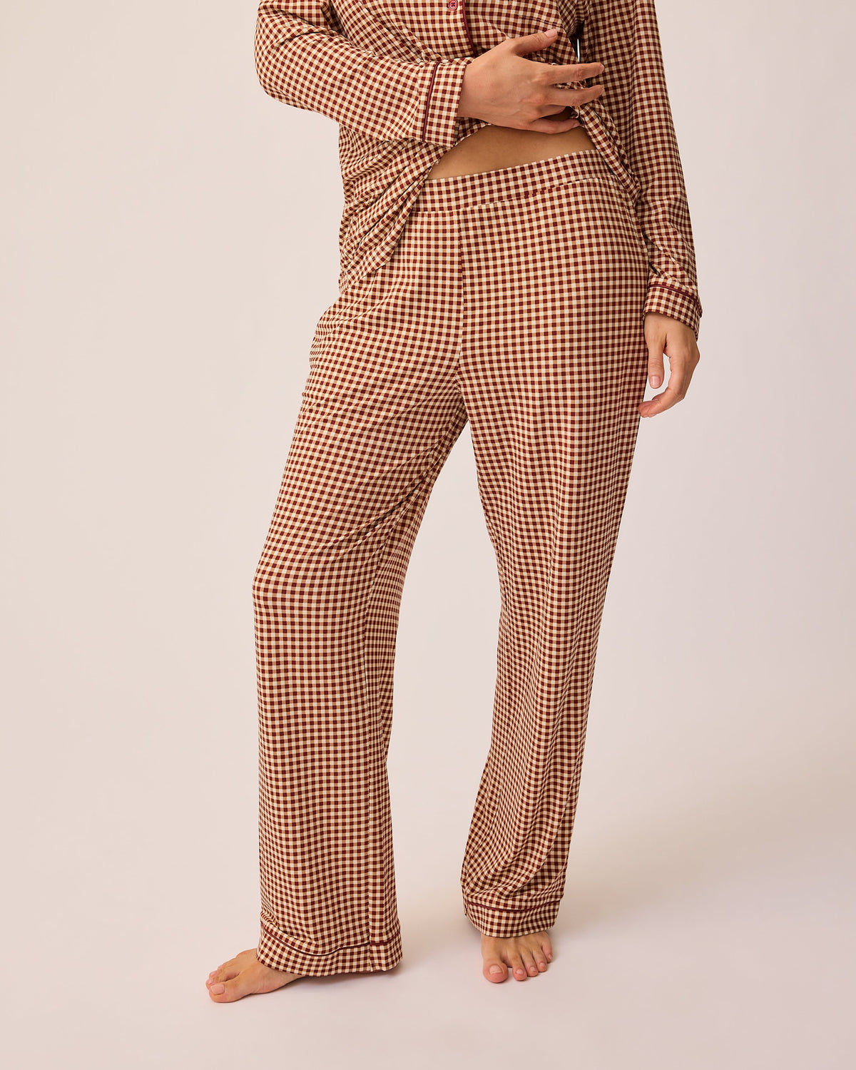Close up of model wearing Clea Bamboo Long Sleeve Pajama Set in Auburn Gingham, on a beige background.