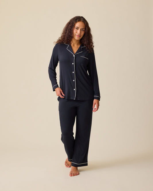Model is wearing Clea Bamboo Long Sleeve Pajama Set in Black on a beige background. @model_info:Sadie is 5'8" and wearing a Medium.