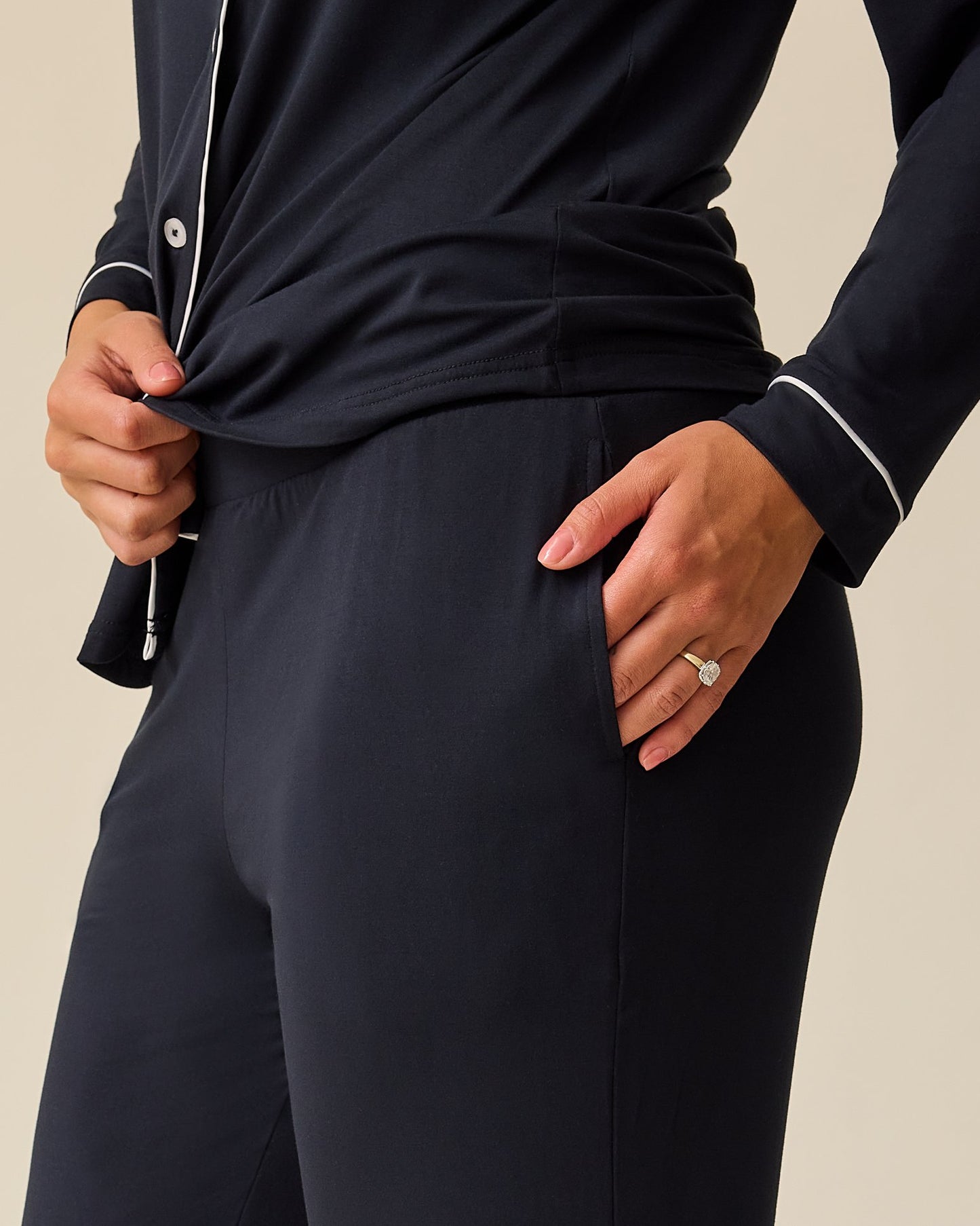 Side view of model wearing Clea Bamboo Long Sleeve Pajama Set in Black on a beige background. 